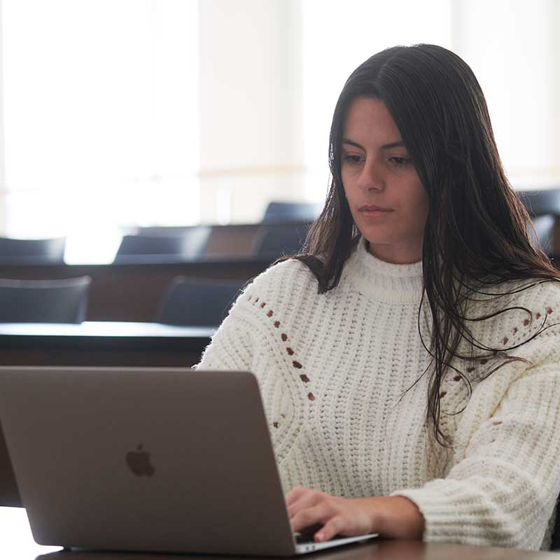 a female student studies on a laptop during a class break