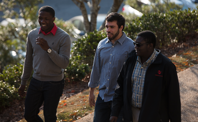 {Three young men walk across campus}