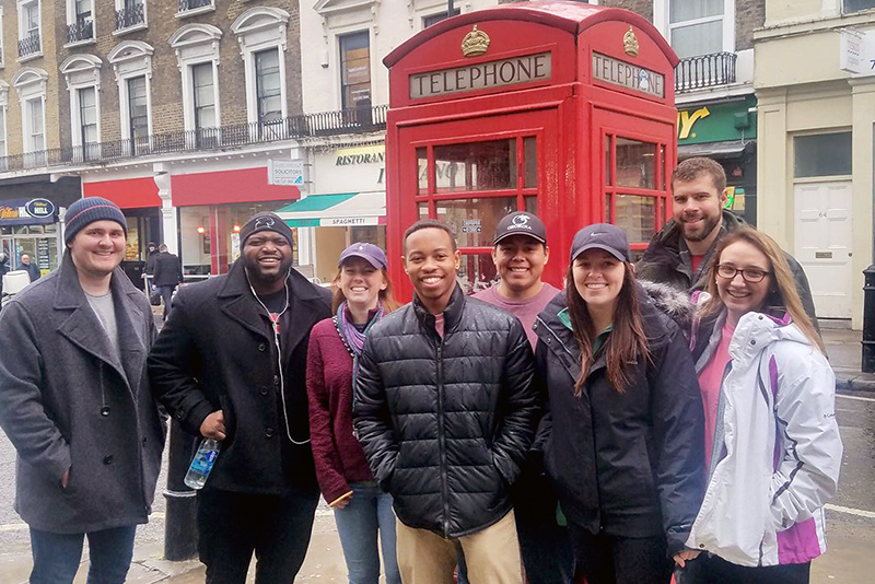 A group of students standing in front of an iconic red phone booth during a trip to London