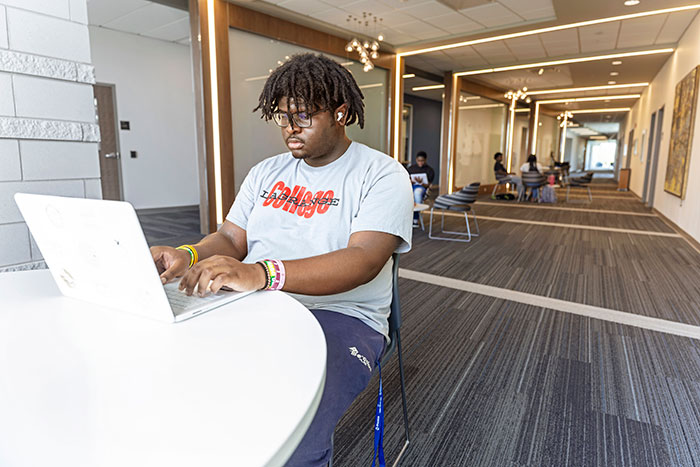A male student works at a computer in an academic building