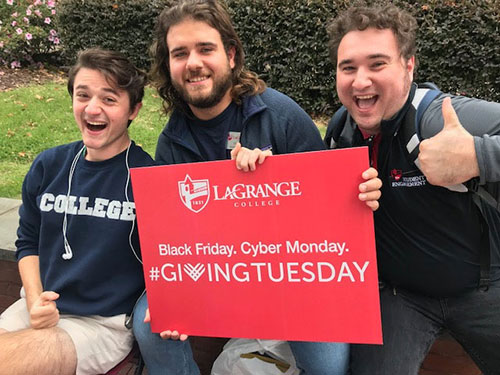Three students pose with a #GivingTuesday sign