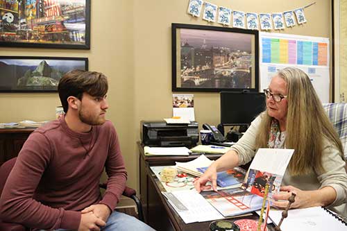 Michele Raphoon, right, speaks with a student in her office