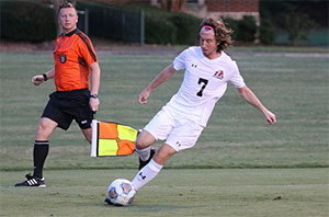 Men's soccer player with control of the ball runs away from the opposing team 