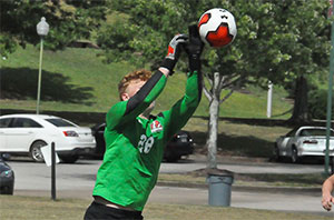 Men's soccer goalie reaching up to stop the ball