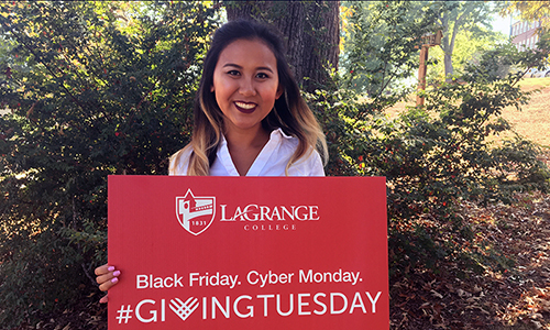 Student poses with college sign that reads "Black Friday. Cyber Monday. #GivingTuesday