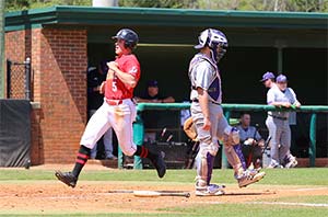 Baseball player touches home as the opposing team's catcher walks away
