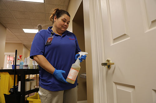 National employee cleans door handle in Smith Hall