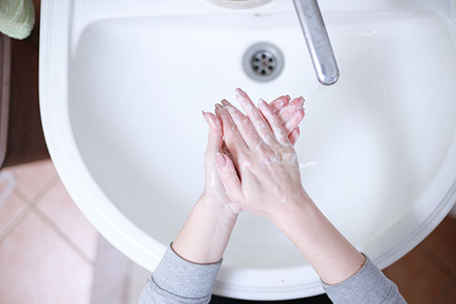 Overhead view of a woman washing her hands at a white bathroom sink