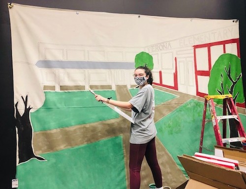 savanna hicks paints a backdrop for her play.