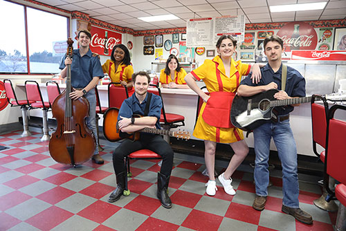 The cast of Pump Boys and Dinettes stand in a diner