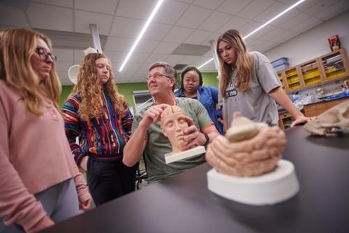 Students watching as professor showcases anatomy model