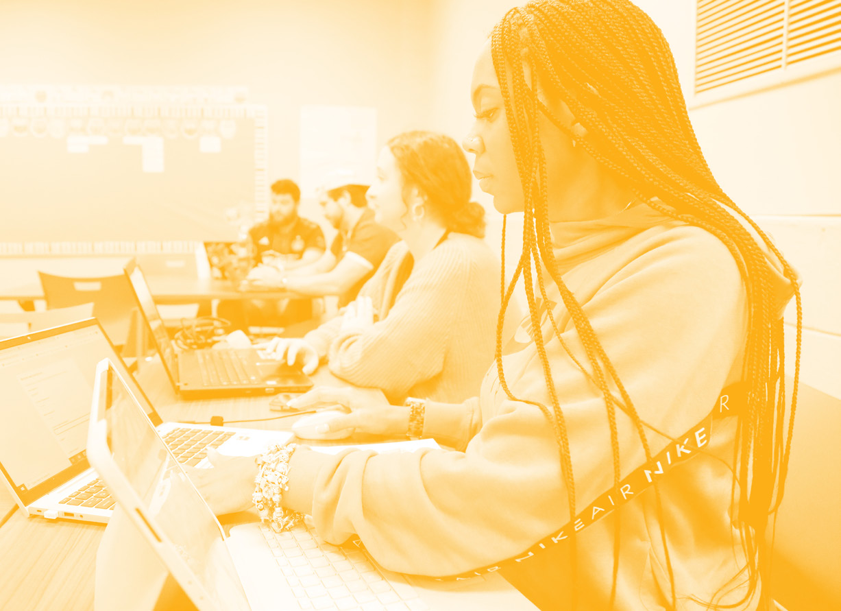 A yellow duo-tone picture of a female student working at her desk