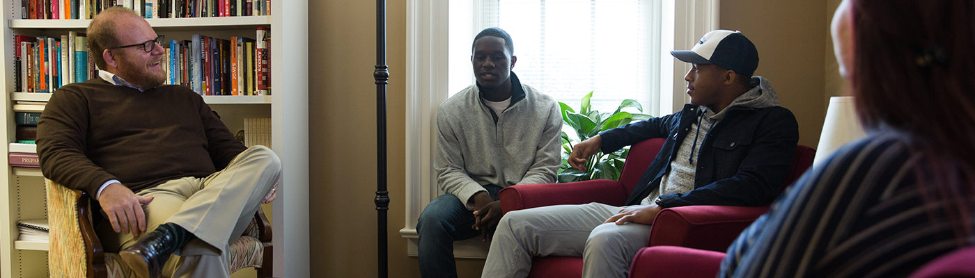 Four students sitting in chairs discussing ideas