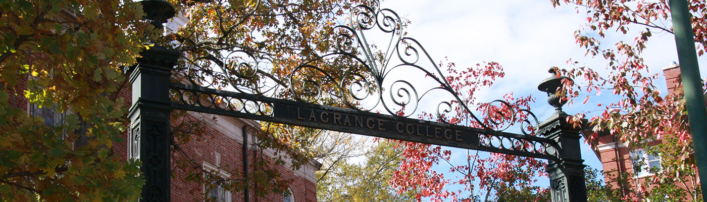 LaGrange College gateway with the sky, campus buildings, and fall leaved trees in the background.