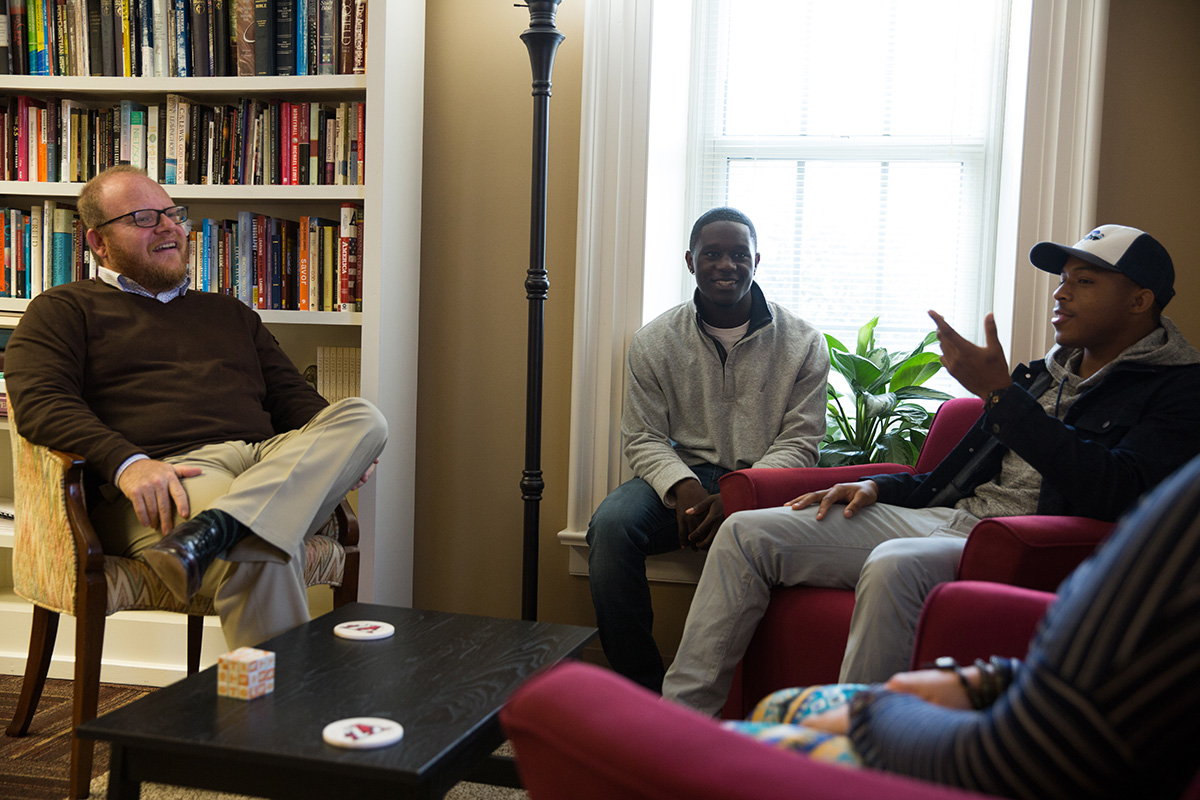 Chaplain Adam Roberts, left, speaks with three students in his office.