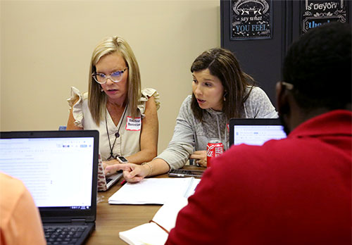 Two students study on a laptop at a crowded table