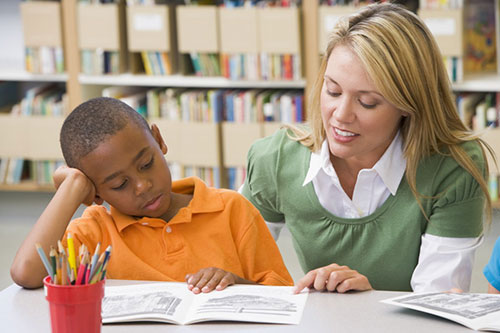 Young teacher working with elementary age male student