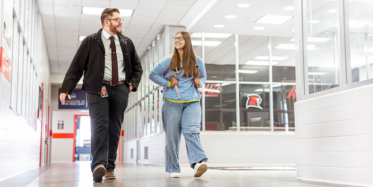 Two students walk down a hallway bathed in white light