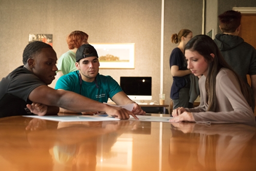 Marketing and Entrepreneurship students reviewing documents at a conference table