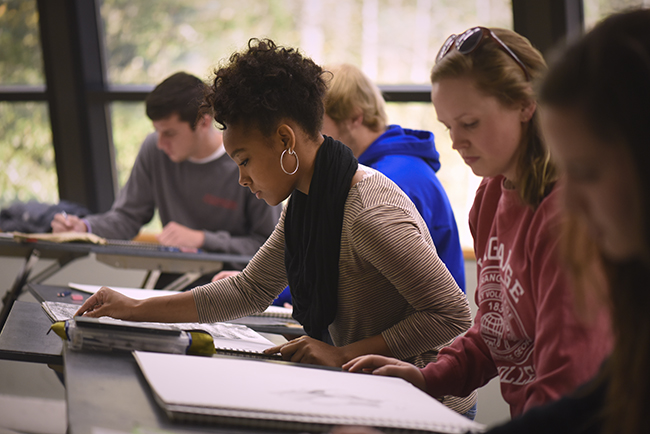 Students working on charcoal sketches in a drawing class