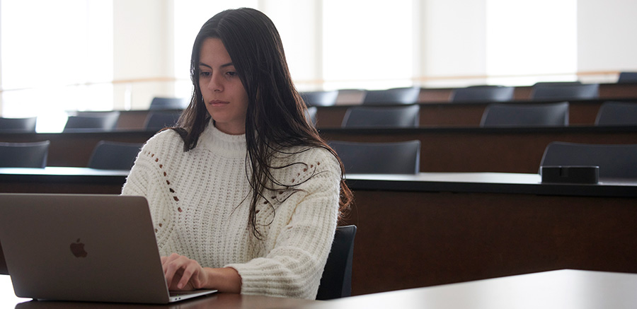 A female student works on a laptop in an open room