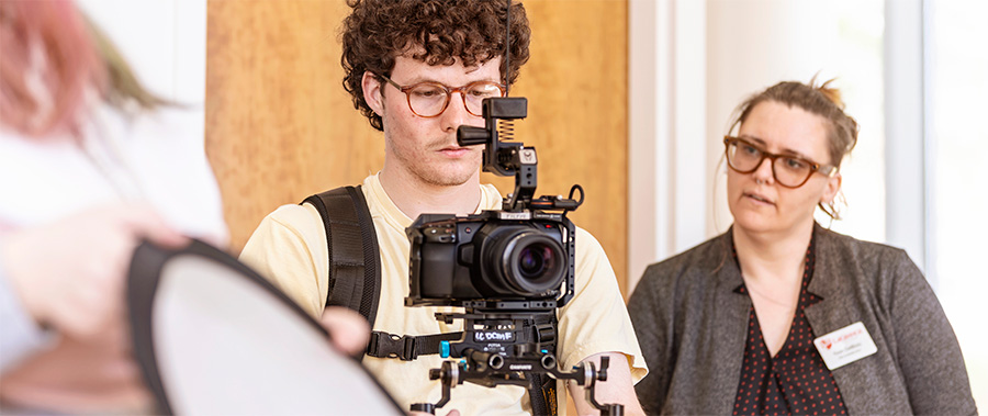 A male film student peers into a video camera