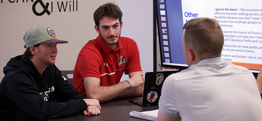 Three students sit around a table while working on a group project
