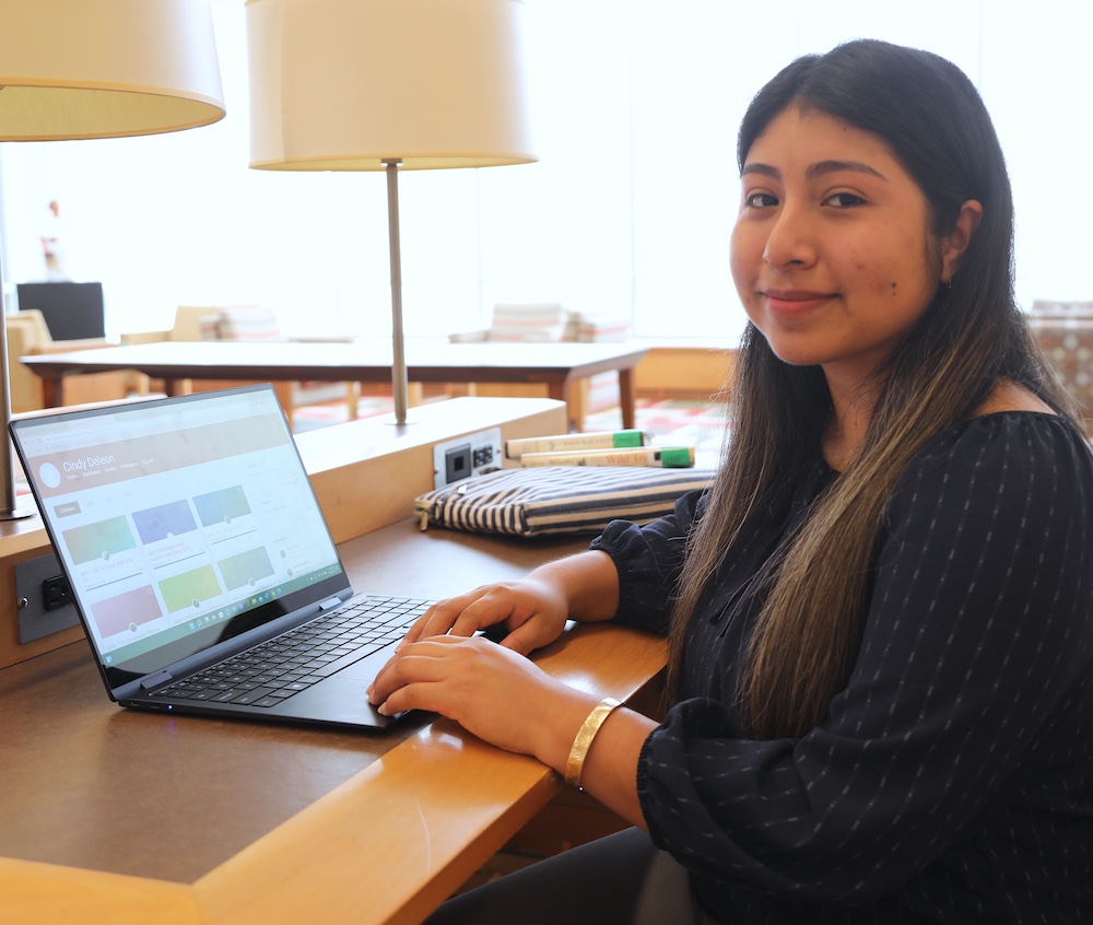 student using laptop smiles at camera