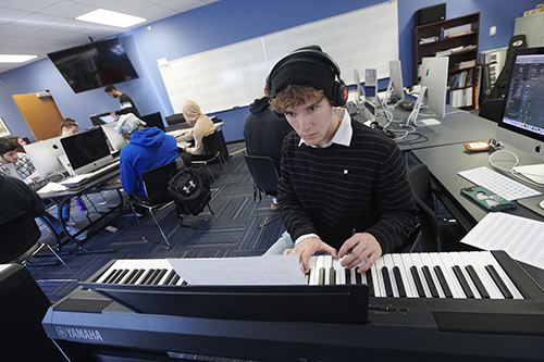 A male student works at a keyboard and computer