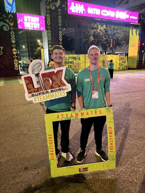 Two men hold signs from Superbowl LIX