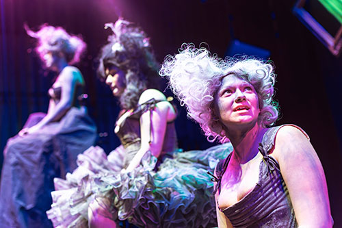Three females in full costume on stage