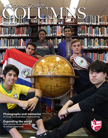 LaGrange College Columns featuring six international students sitting in the library stacks with a large globe