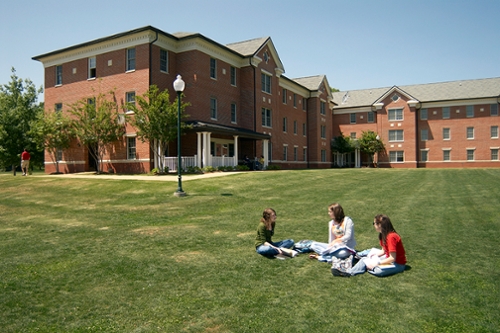 Exterior summer view of Candler Hall with three students studying in the foreground