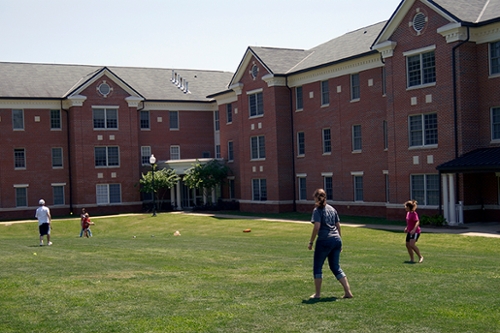 Exterior view of Hawkins Hall with students playing softball in the foreground
