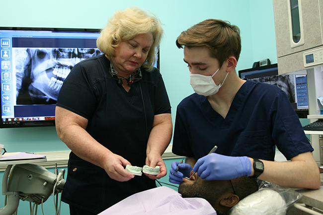 Dentist supervising a student intern with patient in a dentist's chair