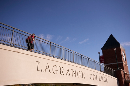 student crossing the LaGrange College pedestrian bridge, which has the college name etched on the side