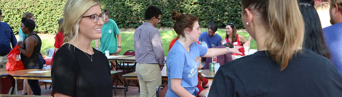 A vendor speaks to students at a busy fair on the college's patio