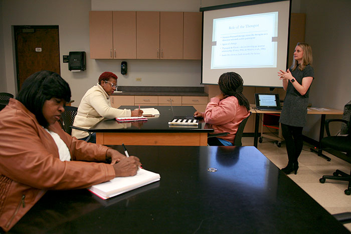 A group of adult students listen to a professor lecture