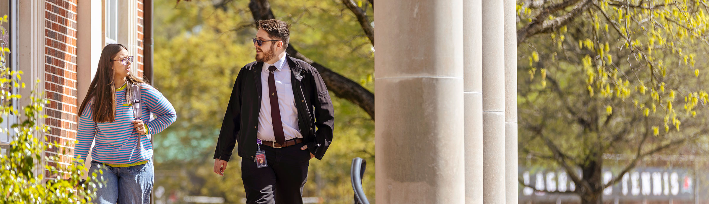 Two students walk down a short staircase in the sunshine
